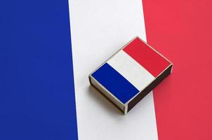 France flag is pictured on a matchbox that lies on a large flag photo