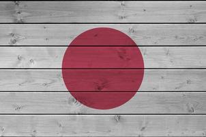 Japan flag depicted in bright paint colors on old wooden wall. Textured banner on rough background photo