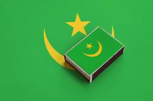 Mauritania flag is pictured on a matchbox that lies on a large flag photo