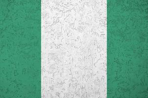 Nigeria flag depicted in bright paint colors on old relief plastering wall. Textured banner on rough background photo