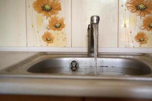 Stainless steel sink plug hole close up full of water and particles of food photo