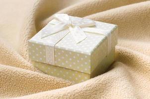 A small gift box in orange with a small bow lies on a blanket of soft and furry light orange fleece fabric with a lot of relief folds. Packing for a gift to your lovely girlfriend photo