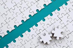 The blue path is laid on the platform of a white folded jigsaw puzzle. The missing elements of the puzzle are stacked nearby. Texture image with space for text photo