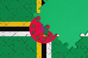 Dominica flag is depicted on a completed jigsaw puzzle with free green copy space on the right side photo