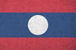 Laos flag depicted in bright paint colors on old relief plastering wall. Textured banner on rough background photo