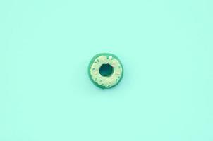 Single small plastic donut lies on a pastel colorful background. Flat lay minimal composition. Top view photo