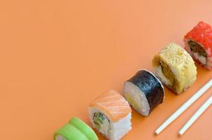 Different types of asian sushi rolls on orange background. Minimalism top view flat lay with Japanese food photo