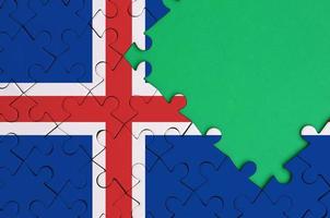 Iceland flag is depicted on a completed jigsaw puzzle with free green copy space on the right side photo