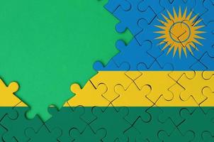 Rwanda flag is depicted on a completed jigsaw puzzle with free green copy space on the left side photo