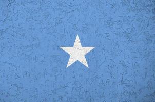 Somalia flag depicted in bright paint colors on old relief plastering wall. Textured banner on rough background photo