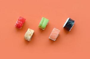 Different types of asian sushi rolls on orange background. Minimalism top view flat lay with Japanese food photo