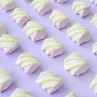 Colorful marshmallow laid out on violet paper background. pastel creative textured pattern. Perspective macro shot photo