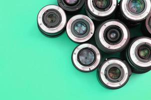 Several photographic lenses lie on a bright turquoise background. Copy space photo