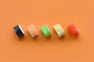 Different types of asian sushi rolls on orange background. Minimalism top view flat lay with Japanese food photo