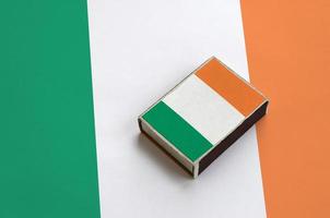 Ireland flag is pictured on a matchbox that lies on a large flag photo