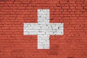 Switzerland flag is painted onto an old brick wall photo