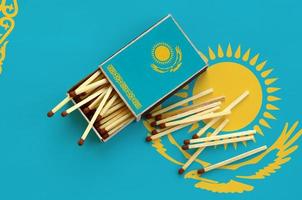 Kazakhstan flag is shown on an open matchbox, from which several matches fall and lies on a large flag photo