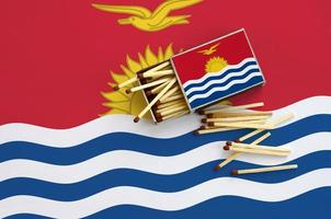 Kiribati flag is shown on an open matchbox, from which several matches fall and lies on a large flag photo