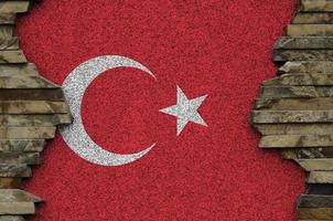 Turkey flag depicted in paint colors on old stone wall closeup. Textured banner on rock wall background photo