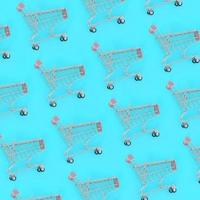 Shopping addiction, shopping lover or shopaholic concept. Many small empty shopping carts perform a pattern on a pastel colored paper background. Flat lay composition, top view photo