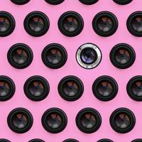 A few camera lenses with a closed aperture lie on texture background of fashion pastel pink color paper in minimal concept. Abstract trendy pattern photo
