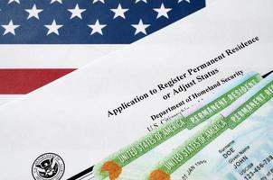 I-485 Application to register permanent residence or adjust status form and green card from dv-lottery lies on United States flag from Department of Homeland Security photo