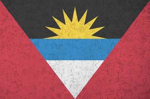 Antigua and Barbuda flag depicted in bright paint colors on old relief plastering wall. Textured banner on rough background photo