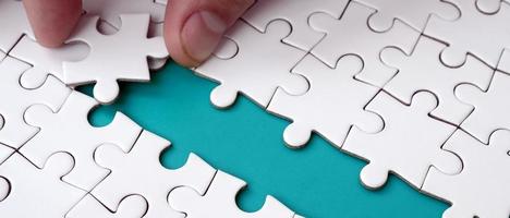 The human hand paves the way to the surface of the jigsaw puzzle, forming a blue space. The concept of overcoming the difficulties on the way to success photo