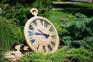 Street clock in a park under branches of trees close up photo