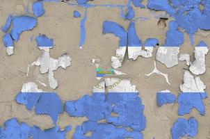 Nicaragua flag depicted in paint colors on old obsolete messy concrete wall closeup. Textured banner on rough background photo