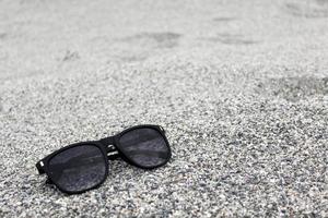 Sunglasses on Sand background Closeup photo