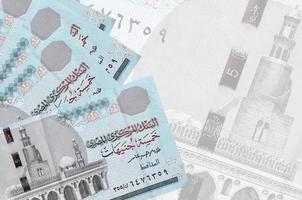 5 Egyptian pounds bills lies in stack on background of big semi-transparent banknote. Abstract business background photo