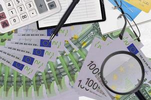 100 Euro bills and calculator with glasses and pen. Tax payment season concept or investment solutions. Searching a job with high salary photo