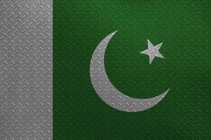 Pakistan flag depicted in paint colors on old brushed metal plate or wall closeup. Textured banner on rough background photo