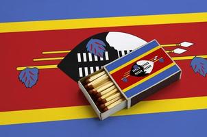 la bandera de swazilandia se muestra en una caja de fósforos abierta, que está llena de fósforos y se encuentra en una bandera grande foto