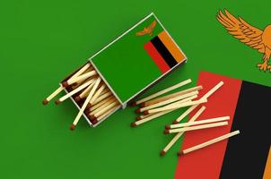 Zambia flag is shown on an open matchbox, from which several matches fall and lies on a large flag photo