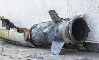 A metal fragment of a military rocket lies on the ground after the shelling of a civilian home. Rocket fire on the city and the horror of war. Ukraine war. The projectile is on the ground. photo