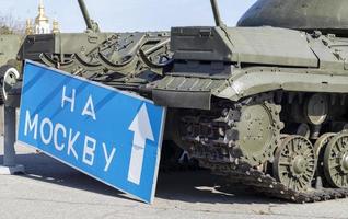 señal de carretera azul con letras blancas cerca del tanque, en el territorio del museo nacional de historia de ucrania. la guerra de rusia contra ucrania. traducción, a moscú. foto