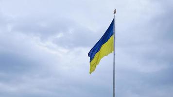 The Ukrainian flag of blue and yellow national colors on the flagpole flutters in the wind against the blue sky and the morning rising sun. The official state symbol of Ukrainians. Patriotism. photo