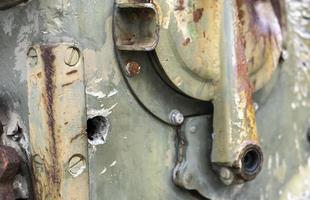 War in Ukraine, a hole in the armor of the BMP, pierced armor. Texture of green camouflage armored metal with damage and holes. Destroyed military armored personnel carrier. photo