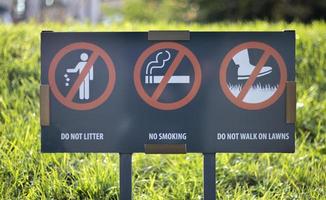 un cartel de información que muestra señales de prohibición en la entrada del parque en un día soleado de verano. no tire basura, no fume, no camine sobre el césped.