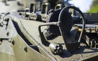 Front headlight with battle tank protection. Very bright searchlight on the tank turret, close-up. Armored infantry fighting vehicle. Fragment of an old armored personnel carrier, khaki headlight. photo