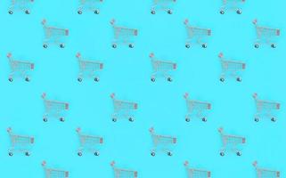 Shopping addiction, shopping lover or shopaholic concept. Many small empty shopping carts perform a pattern on a pastel colored paper background. Flat lay composition, top view photo
