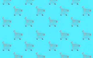 Shopping addiction, shopping lover or shopaholic concept. Many small empty shopping carts perform a pattern on a pastel colored paper background. Flat lay composition, top view photo