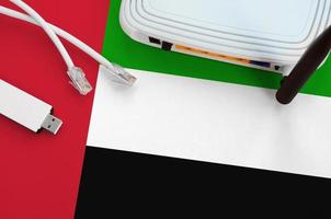 United Arab Emirates flag depicted on table with internet rj45 cable, wireless usb wifi adapter and router. Internet connection concept photo