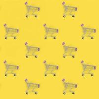 Shopping addiction, shopping lover or shopaholic concept. Many small empty shopping carts perform a pattern on a pastel colored paper background. Flat lay composition, top view photo