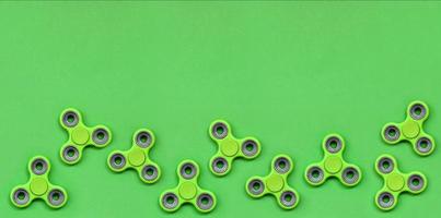 muchos fidget spinners verdes se encuentran en el fondo de textura del papel de color verde pastel de moda en un concepto mínimo foto