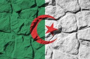 bandera de argelia representada en colores de pintura en el primer plano de la pared de piedra antigua. banner texturizado sobre fondo de pared de roca foto