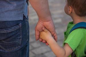 A father holds his son's hand while walking down a city street.  Travel. Lifestyle in the city. Center, streets. photo