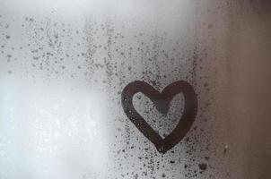 The heart is painted on the misted glass in winter photo